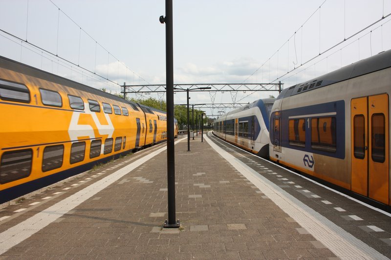 Sprinter op het station. Een intercity rijdt net voorbij